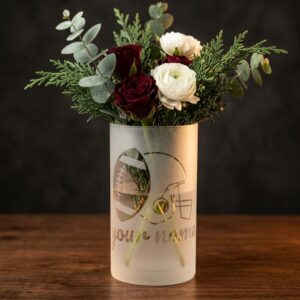 Frosted glass vase with a clear football and helmet design and "your name" placeholder script, holding red and white roses with greenery on a wooden table